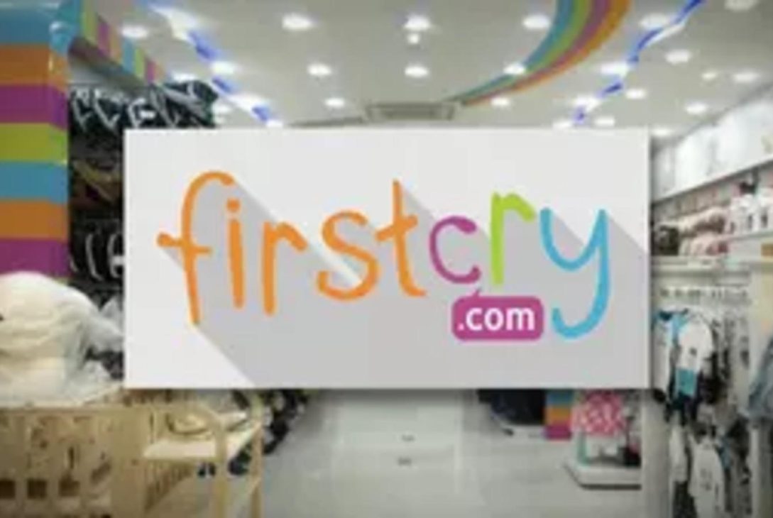 FirstCry.com logo displayed in a brightly lit retail store.