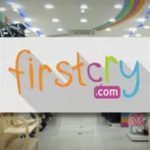 FirstCry.com logo displayed in a brightly lit retail store.